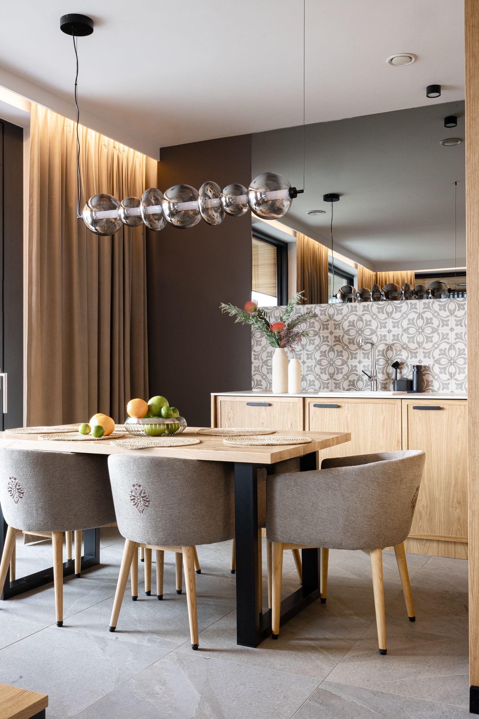 Jadalnia z drewnianym stołem, szarymi krzesłami i kulistym żyrandolem