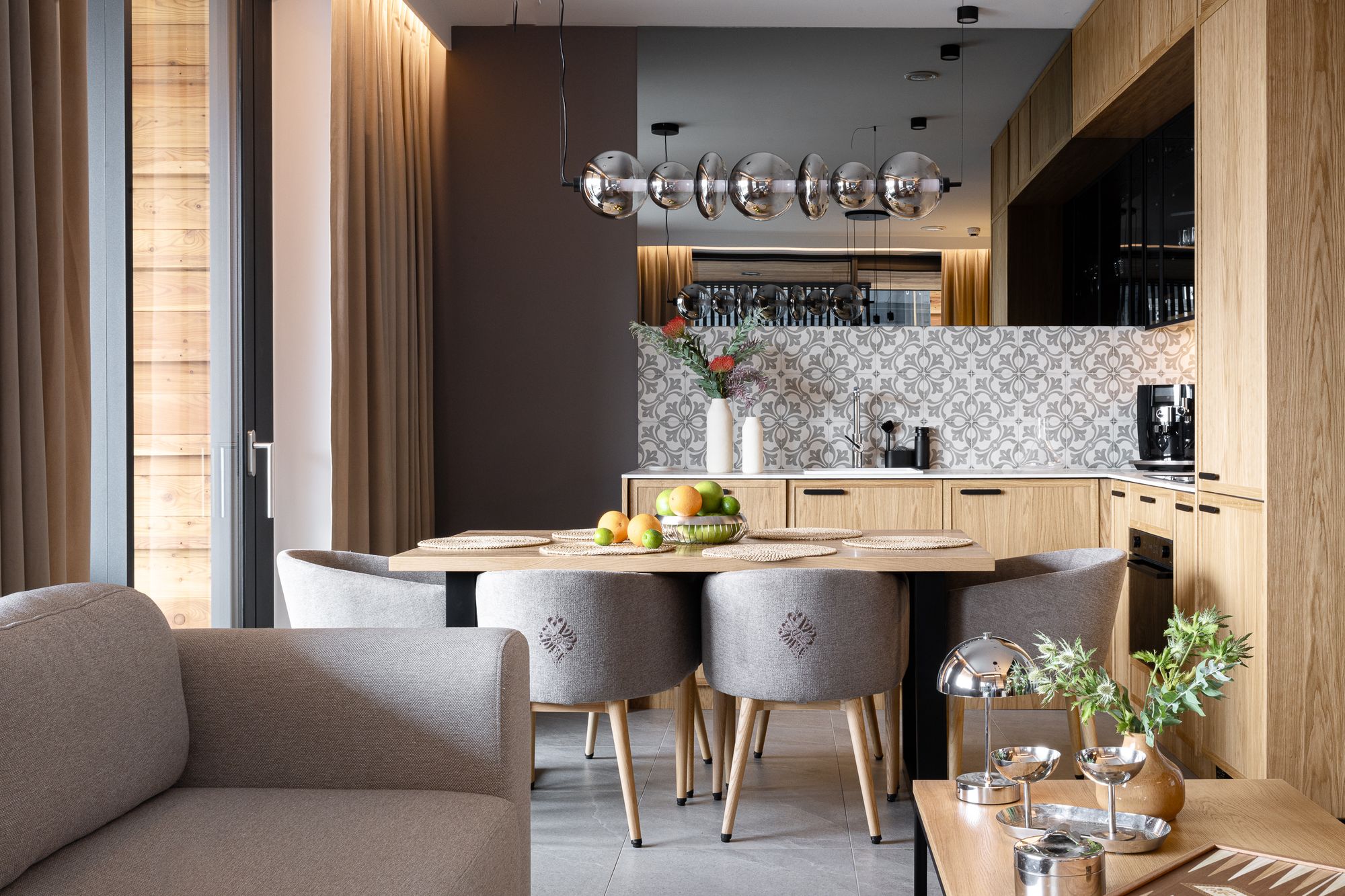 Nowoczesna jadalnia: drewniany stół, szare krzesła, kuliste lampy