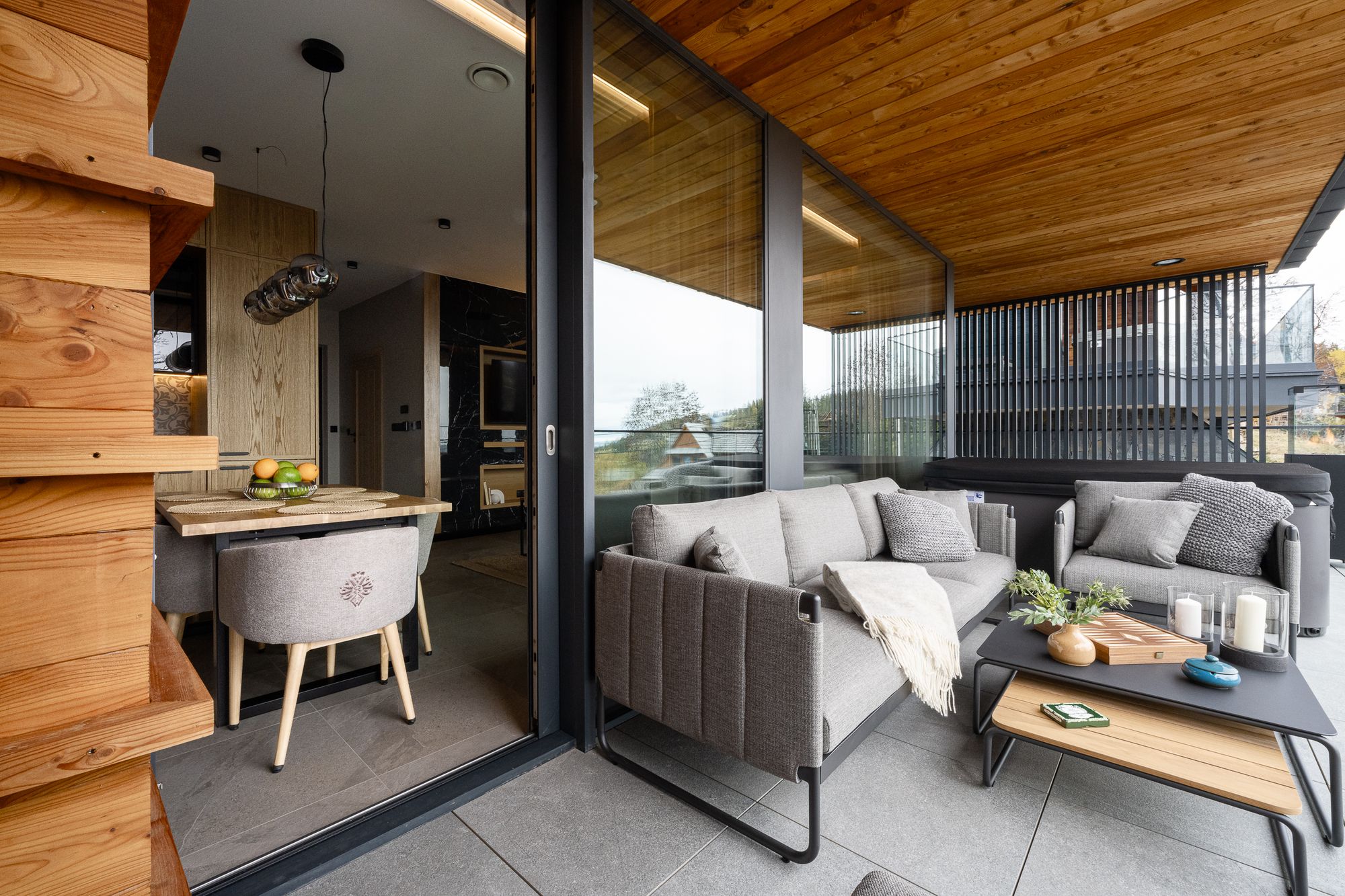 Nowoczesny balkon z sofą, drewnianym dachem i szklanymi drzwiami