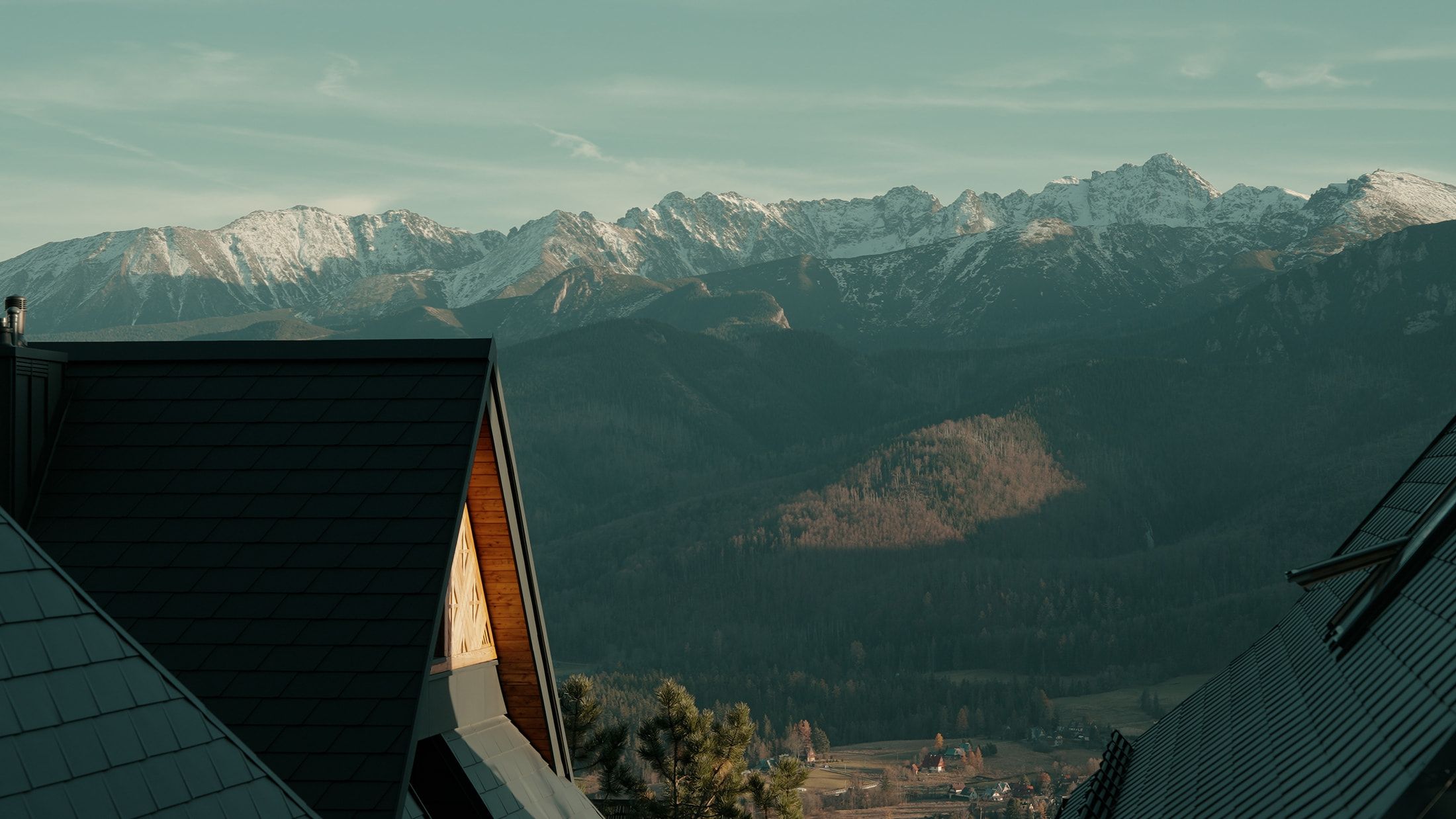 Ośnieżone góry nad wioską, widok na dachy domów w dolinie