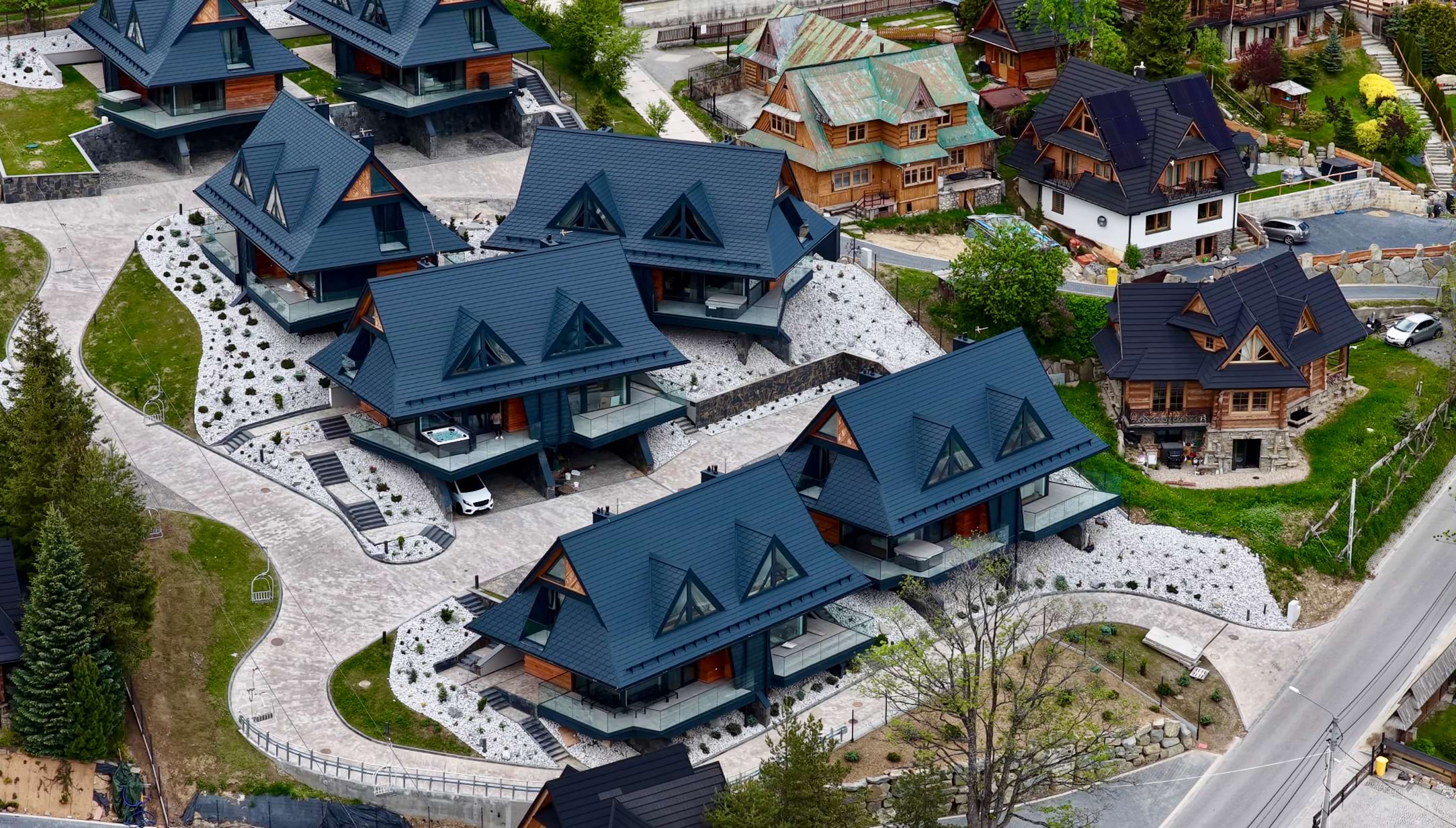Górskie osiedle domów z ciemnoniebieskimi dachami, otoczone skałkami